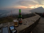 A kindle, phone and beer pictured with the volcano in the background.