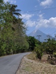 A road leading to a volcano which has smoke coming out od it
