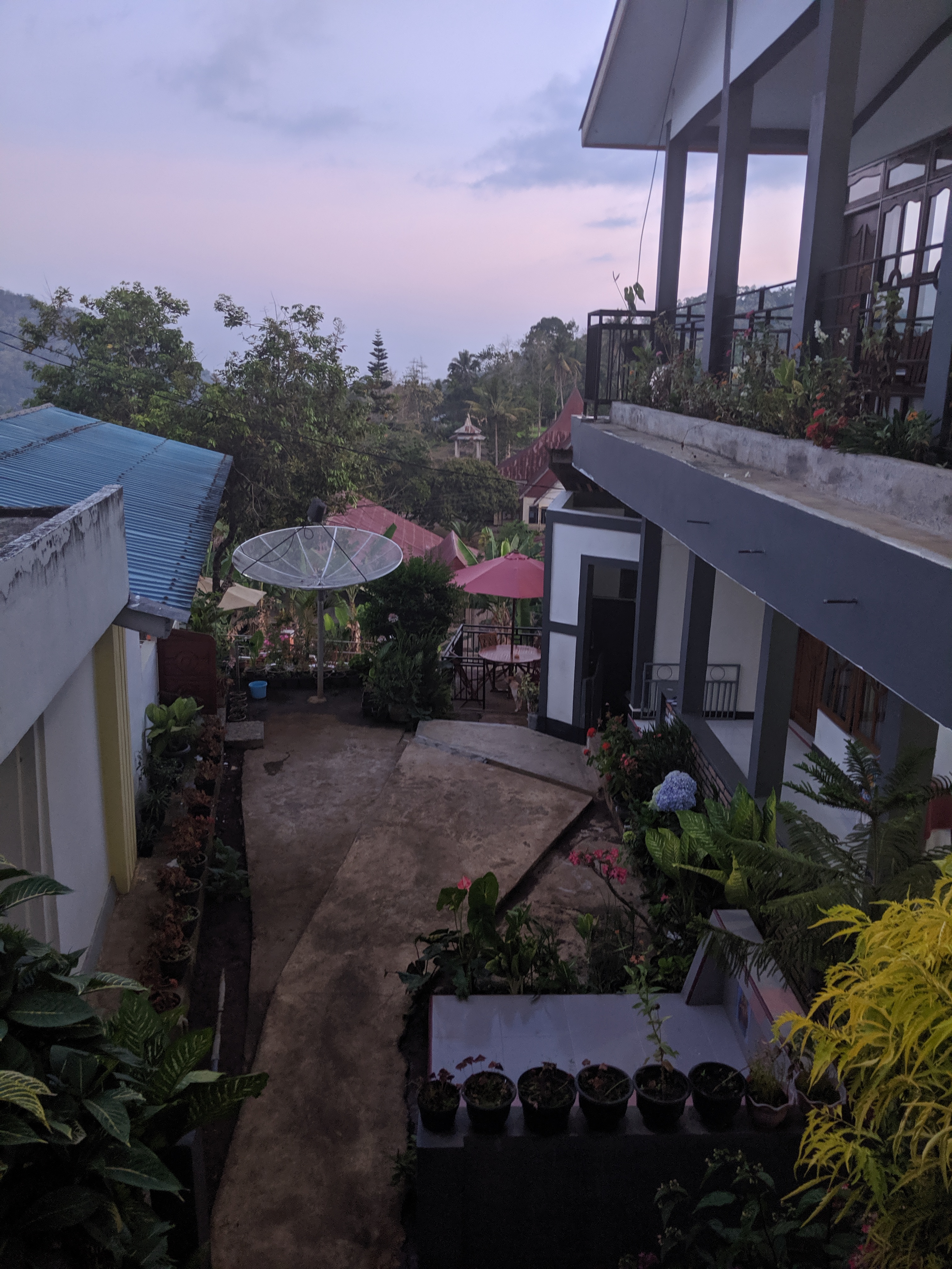Looking through the middle of a homestay with rooms on the right and two family graves below.