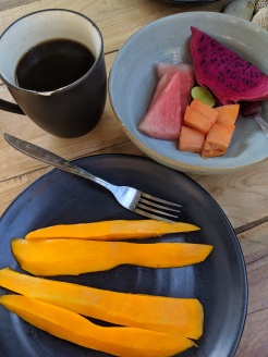 breakfast dishes full of colourful fruit alongside a cup of coffee